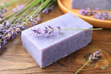 Soap bar and lavender flowers on wooden table, closeup