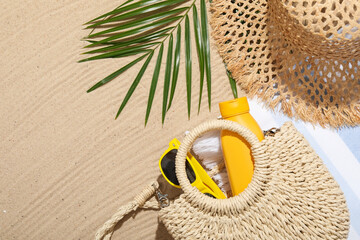 Different beach accessories and palm leaf on sand outdoors, flat lay. Space for text