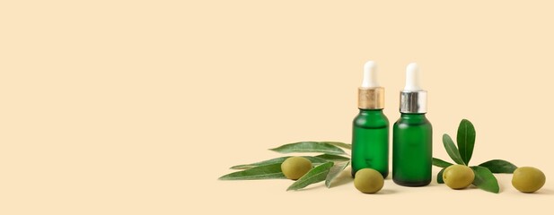 Bottles of olive essential oil on beige background with space for text