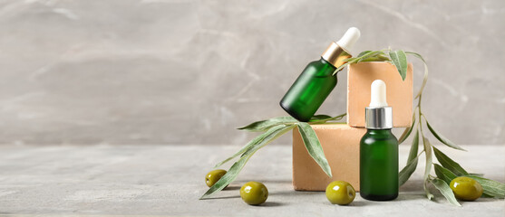 Bottles of olive essential oil on grey background with space for text