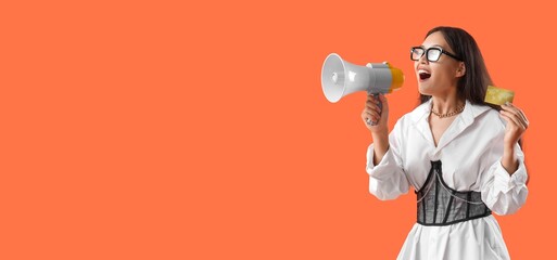 Young Asian woman with credit card and megaphone on orange background with space for text