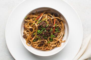 Overhead view of mongolian ground beef noodles in a white bowl