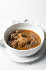 Overhead view of Nigerian goat pepper soup in a white soup plate, top view of goat meat pepper soup in a plate, traditional goat peppersoup in a white bowl