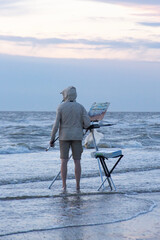 A men painting looking out over the sea 