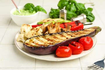 Plate with grilled vegetables and basil on white tile table