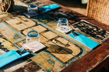 Decorative outdoor dining table setting with blue napkins and glassware in a sunny garden environment