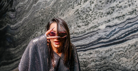 Fashionable young woman posing, wearing sunglasses and bright clothes.