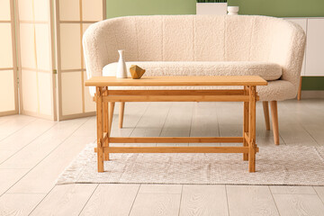 Wooden coffee table with vase and decor in interior of living room