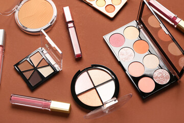 Beautiful palettes of eyeshadows and different decorative cosmetics on brown background