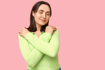 Obraz premium Young woman hugging herself on pink background