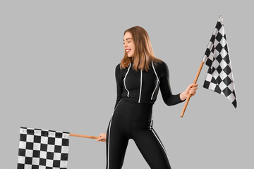 Beautiful young woman with racing flags on grey background