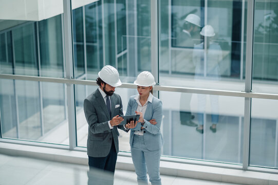 Architects using tablet discussing blueprint in modern building