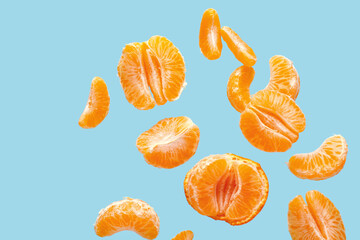 Flying sweet peeled mandarins on blue background