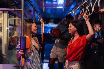Two young women talking on a moving bus at night