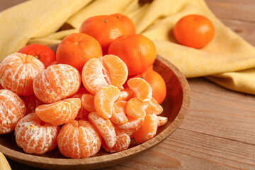 Bowl with peeled tangerines on wooden table