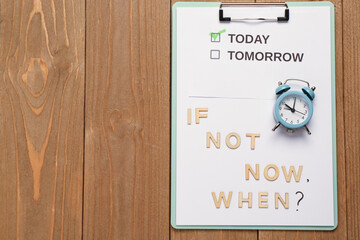 Clipboard with text IF NOT NOW WHEN? and alarm clock on wooden background. Top view