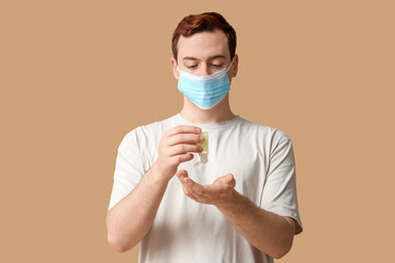 Young man with sanitizer on beige background