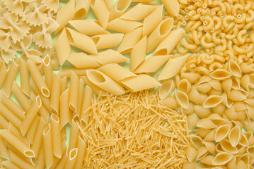 Different types of delicious uncooked pasta on table