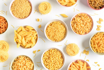 Bowls with different raw tasty pasta on white background