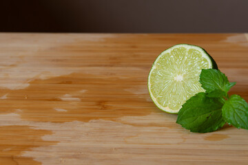 mint and cut lime on a wet wooden cutting board with contrast background