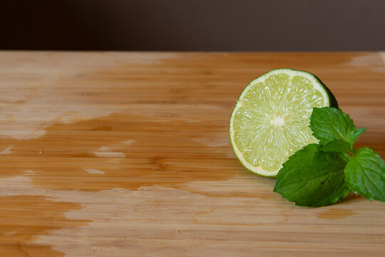 mint and cut lime on a wet wooden cutting board with contrast background