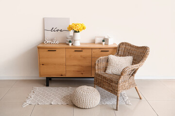 Armchair near chest of drawers with daffodil flowers in living room