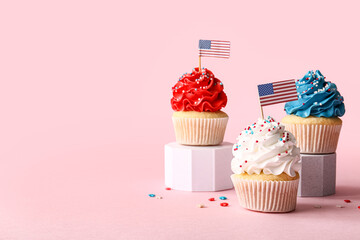 Tasty patriotic cupcakes with USA flags on pink background. American Independence Day
