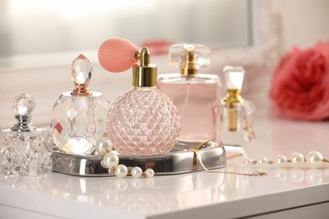 Bottles of different perfumes and accessories on dressing table indoors, closeup