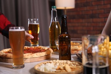 Friends with beer and snacks at table, closeup