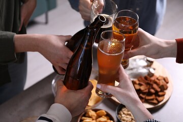 Friends clinking glasses of beer at table, closeup