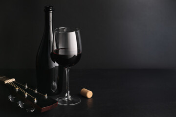 Acoustic guitar and red wine on black table. Space for text