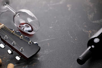 Acoustic guitar and red wine on black table, closeup. Space for text
