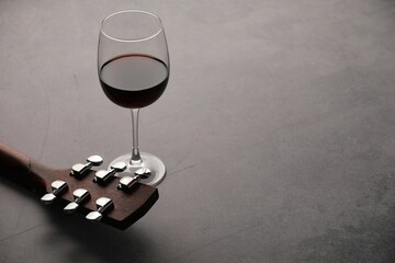 Acoustic guitar and red wine on grey table, closeup. Space for text