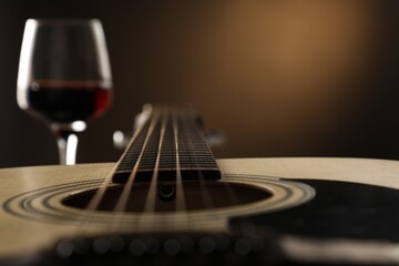 Acoustic guitar and glass of red wine on black background, closeup. Space for text
