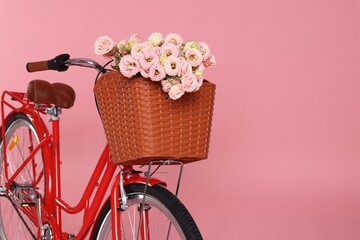 Bicycle with basket of beautiful flowers on pink background. Space for text