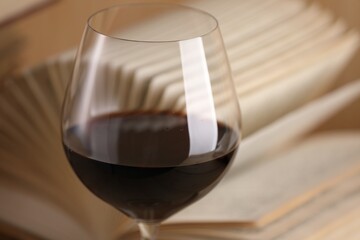 Glass of red wine and open book on table, closeup