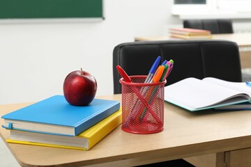 Different school stationery and red apple on wooden table indoors