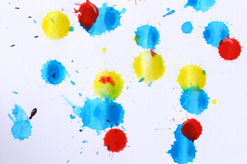 Various color paint drops on paper, causing dispersion of color.