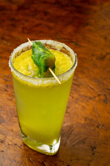 Creative frozen mango or lulo Margarita cocktail with a salt rim and a green ice pop (popsicle)...