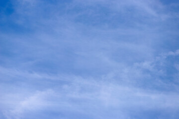 A wide expanse of clear blue sky, featuring a few very thin and sparse white clouds, almost transparent, creating an atmosphere of lightness and serenity.