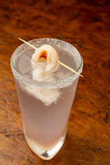 Close-up of a Chilled Lychee Cocktail in a Salt-Rimmed Highball Glass with Whole Lychee Garnish on a Rustic Wooden Surface