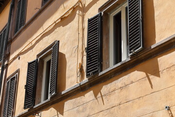Peach-colored facade of a house on Via dell'Opio nel Corso west side featuring windows of...