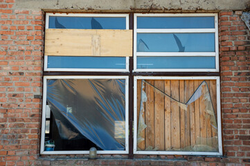 Broken and boarded windows illustrate neglect in an abandoned structure, highlighting urban decay...