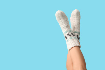 Legs of young woman in knitted socks on blue background