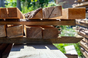 Sunlight filters through leaves, highlighting a stack of wooden planks resting on a wooden surface...