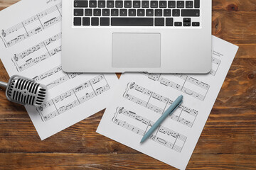 Music sheets with laptop and microphone on wooden background