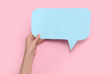 Female hand with blank paper speech bubble on color background, closeup