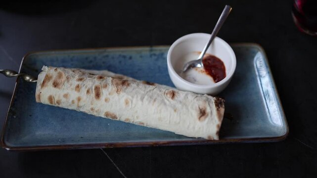 Juicy lula kebab wrapped in grilled lavash served on a ceramic plate with creamy and spicy sauces capturing the rich flavor and aroma of traditional Caucasian cuisine