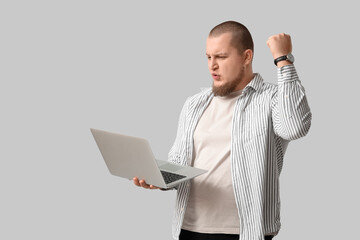 Young man with laptop showing yes gesture against white background
