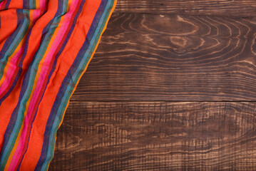 Colorful typical mexican tablecloth on wooden table. Background, texture.